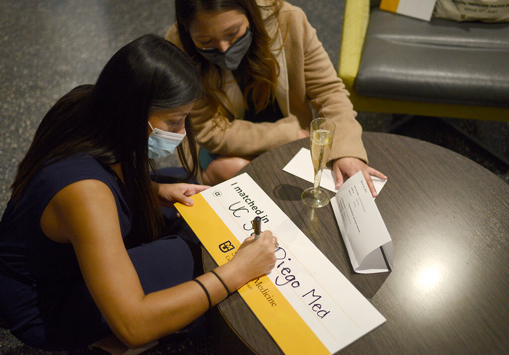 Alejandra Rodriguez, left, and Paula Rodriguez write on a sign